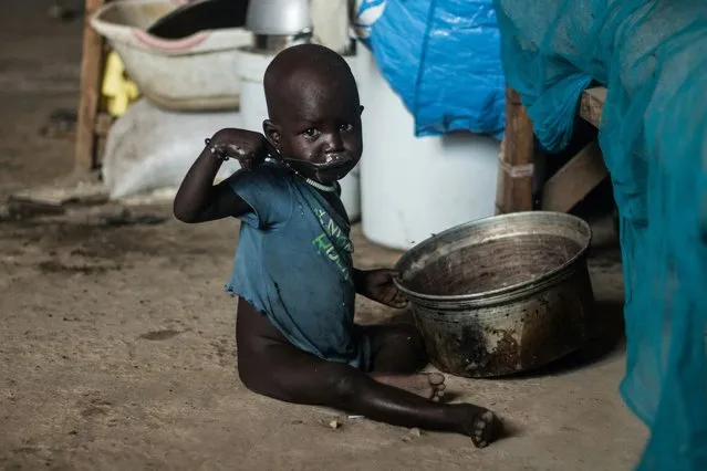 A child eats porridge sitting on the floor of a shelter at Mangateen Internal Displaced persons (IDPs) center in Juba on November 17, 2018. Some 5000 IDPs have been relocated to a new resettlement centre from the UN Protection of Civilians site (POC) after ethnic clashes erupted in the POC. (Photo by Akuot Chol/AFP Photo)