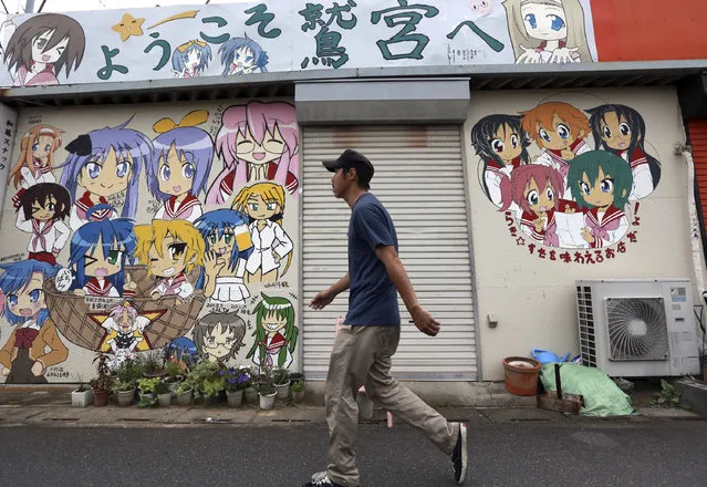 A man walks by an eatery with its facade painted with letters that read “Welcome to Washinomiya” and the characters of a TV animation series “Lucky Star” or “Raki Sta” near Washinomiya Jinja shrine in Kuki, Saitama prefecture, north of Tokyo, Friday, September 16, 2016. Eighty-eight places in Japan are going to be designated “animation spots” to encourage tourism – using train stations, school campuses, rural shrines and other fairly everyday places where popular “manga” characters are depicted. One shoo-in for the list, according to organizers, is Washinomiya Jinja, a picturesque shrine, which is a familiar scene in the comic by Kagami Yoshimizu, which later became the TV animation series. (Photo by Eugene Hoshiko/AP Photo)