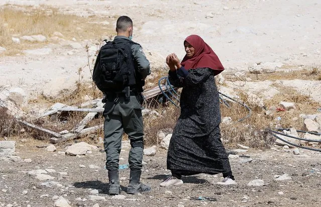 A Palestinian woman gestures towards Israeli border police guard as an Israeli bulldozer demolishes a house in the West Bank area of Masafer near Yatta, 02 September 2020. Israel on a regular basis demolishes Palestinians' houses in the West Bank citing missing building permits for Area. (Photo by Abed Al Hashlamoun/EPA/EFE)