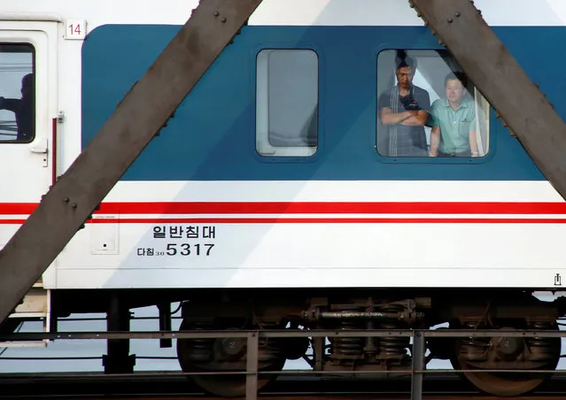 Men look out of a the window of a train that travels across Friendship Bridge from North Korea to China's Dandong, Liaoning province, September 12, 2016. (Photo by Thomas Peter/Reuters)