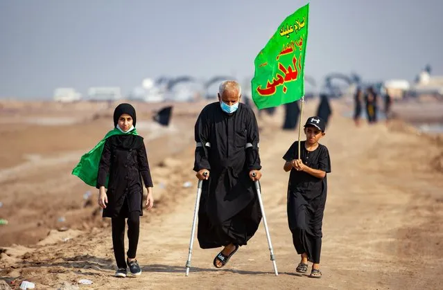 A disabled Iraqi Shiite Muslim man and children who began their march from the southern port city of al-Faw, walk through Basra on their way to the holy city of Karbala, ahead of the Arbaeen religious festival, on September 17, 2020. Each year, pilgrims converge in large numbers to the holy Iraqi cities of Najaf and Karbala ahead of Arbaeen, which marks the 40th day after Ashura, commemorating the seventh century killing of Prophet Mohammed's grandson Imam Hussein This year however, the Iraqi authorities prevented foreign visitors from entering Iraq to participate, due to the novel coronavirus crisis. (Photo by Hussein Faleh/AFP Photo)