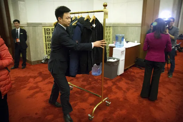 A staff member pushes a coat rack through the Great Hall of the People in Beijing, Friday, March 2, 2018. The annual meetings of China's top legislative bodies are set to begin on Saturday, during which the two-term limit on China's presidency is expected to be removed. (Photo by Mark Schiefelbein/AP Photo)