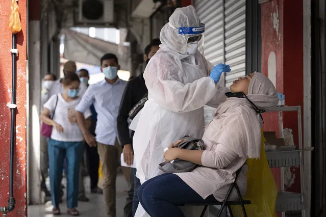 A doctor collects a sample for a coronavirus test outside a clinic in Kajang on the outskirts of Kuala Lumpur, Malaysia, Friday, October 23, 2020. Malaysia restricted movements in its biggest city Kuala Lumpur, neighbouring Selangor state and the administrative capital of Putrajaya from Wednesday in an attempt to curb a sharp rise in coronavirus cases. (Photo by Vincent Thian/AP Photo)