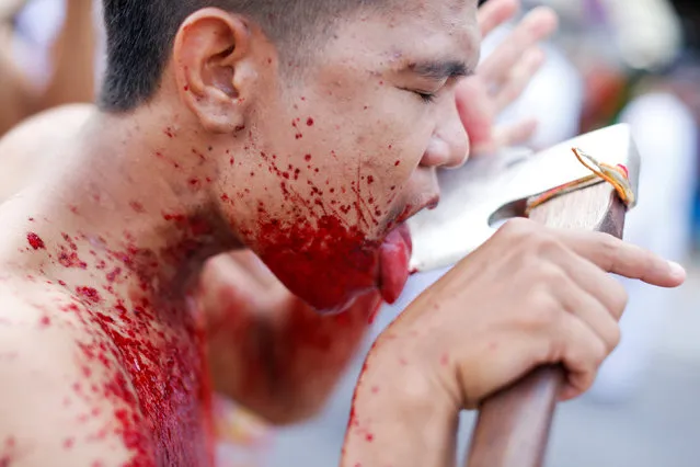 A devotee of the Chinese Samkong Shrine walks while cutting his tongue with an axe during a procession celebrating the annual vegetarian festival in Phuket, Thailand October 4, 2016. (Photo by Jorge Silva/Reuters)