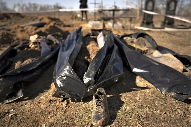 Three freshly exhumed bodies lie on the ground in a cemetery on the outskirts of Borodyanka, Ukraine, Thursday, March 2, 2023. Nearly a year after towns and villages near Kyiv were retaken from Russian troops who had seized territory as they raced toward Kyiv at the start of their invasion of Ukraine, authorities are still exhuming the bodies of civilians hastily buried in makeshift graves. (Photo by Vadim Ghirda/AP Photo)
