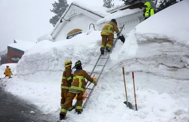 Mammoth Lakes Fire Department firefighters use a ladder on a snowbank while responding to a propane heater leak and small fire at a shuttered restaurant surrounded by snowbanks, in the wake of an atmospheric river event, on March 12, 2023 in Mammoth Lakes, California. Snowpacks and snow drifts can bear weight on delicate gas lines which can potentially break and create a dangerous pocket of explosive gas. The eastern Sierra Nevada mountains currently hold 243 percent of its regular snowpack for this time of the year. California is bracing for another powerful atmospheric river event, bringing more snow to higher elevations and rain to lower elevations, beginning tomorrow. (Photo by Mario Tama/Getty Images)