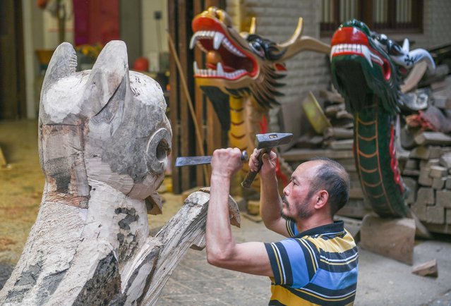 Cheng Bingshou, a provincial-level intangible cultural heritage inheritor, carves moulds for the head of a dragon boat as the Dragon Boat Festival approaches on May 17, 2024 in Yongzhou, Hunan Province of China. As the Dragon Boat Festival approaches, Dao County in Yongzhou City, known as the "Hometown of Dragon Boats", has begun to build a batch of new dragon boats to welcome the annual dragon boat race. (Photo by Jiang Keqing/VCG via Getty Images)