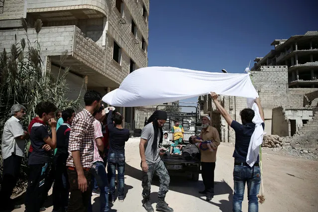 Men hold a white cloth over actors as they perform a scene in a film directed by Humam Husari in the rebel-held besieged town of Zamalka, in the Damascus suburbs, Syria September 19, 2016. A Syrian filmmaker whose harrowing footage of sarin gas victims in 2013 was seen around the world is using his experience of the attack and conflict to make a drama looking at why people take up arms in a war which began as a peaceful revolution. Humam Husari's self-financed short film explores the chemical attack near Damascus through the eyes of a rebel fighter who lost his wife and child but was denied time to bury them. Instead, he is called to defend his town from a government offensive. The story is based on real-life events, he said. “We need to understand how people were pushed into this war and to be part of it”, said Husari, 30. “I am talking about a story that I lived with. They are real characters”. (Photo by Bassam Khabieh/Reuters)