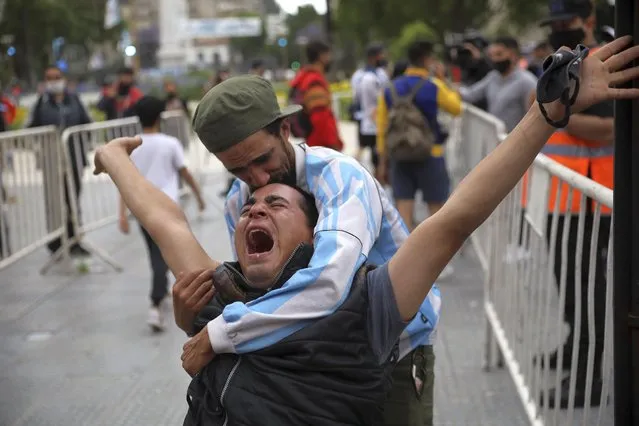 Mourners embrace as they wait to see Diego Maradona lying in state outside the presidential palace in Buenos Aires, Argentina, Thursday, November 26, 2020. (Photo by Rodrigo Abd/AP Photo)