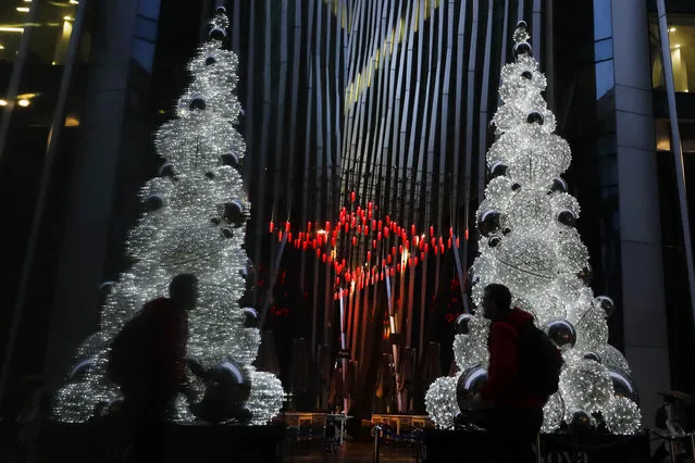 A man is reflected in a window as he walks past a Christmas tree in London, Thursday, December 3, 2020. The European Union on Thursday hit back at a British minister's claim that U.K. vaccine regulators were better than other countries, stressing “this is not a football competition”. This came after Britain became the first country in the world to authorize Pfizer's rigorously tested COVID-19 vaccine Wednesday. (Photo by Kirsty Wigglesworth/AP Photo)