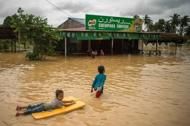 Children play in floodwaters near their house in Chempaka, near Kota Bahru on December 28, 2014. Malaysia on December 28 pledged more funds to help over 160,000 people hit by the country's worst flooding in decades, as forecasters warned fresh rain could hamper efforts to relieve thousands left stranded by the waters. (Photo by Mohd Rasfan/AFP Photo)