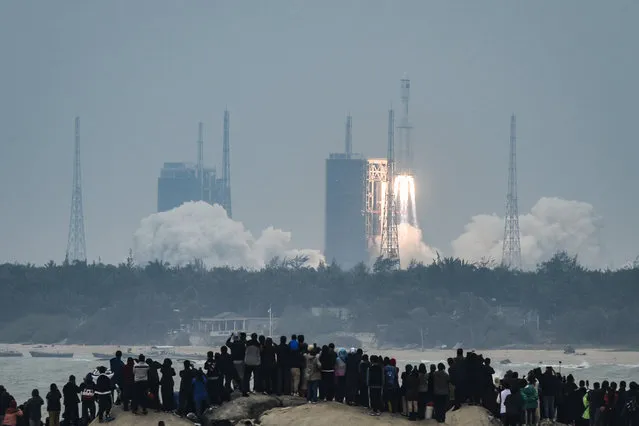 People watch a Long March-8 rocket, the latest China's Long March launch vehicle fleet, lifting off from the Wenchang Space Launch Center in southern China's Hainan province on December 22, 2020. (Photo by AFP Photo/China Stringer Network)