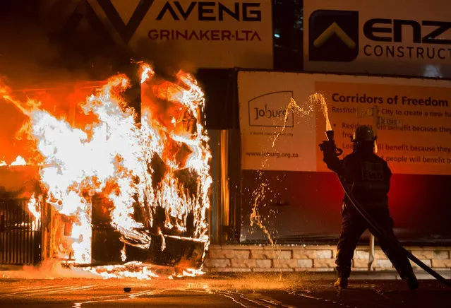 A fireman attempts to extinguish a burning bus in Braamfontein, Johannesburg, South Africa, Tuesday, October 25, 2016. (Photo by Yeshiel Panchia/AP Photo)