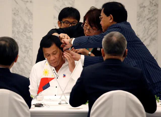 Philippine President Rodrigo Duterte is helped by interpreters to attach an earphone as he attends a luncheon meeting with Japanese business leaders in Tokyo, Japan October 26, 2016. (Photo by Kim Kyung-Hoon/Reuters)