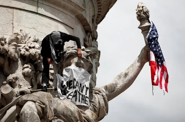 A banner and a U.S. flag are placed on the Monument a la Republique during a protest against police brutality and the death in Minneapolis police custody of George Floyd, at the Place de la Republique square in Paris, France on June 13, 2020. (Photo by Benoit Tessier/Reuters)