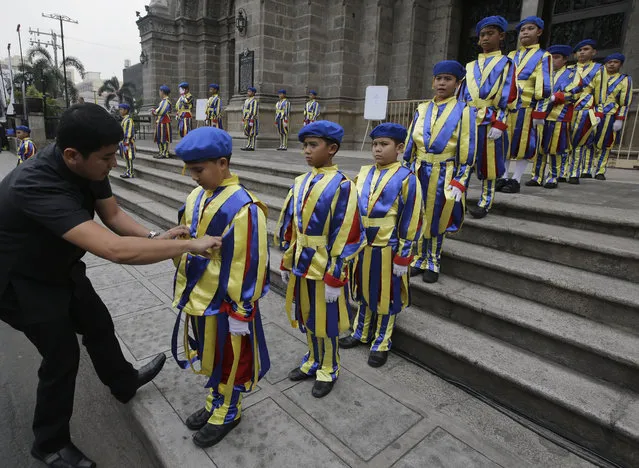 A Catholic priest adjusts the uniform of boys who are dressed as Vatican Swiss guards during a rehearsal for the visit of Pope Francis outside the Manila Cathedral Wednesday, January 14, 2015 in Manila, Philippines. (Photo by Bullit Marquez/AP Photo)