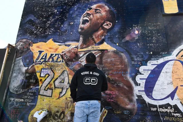 Caesar Mendoza takes a snapshot of a mural of Kobe Bryant in an alley near Staples Center in downtown Los Angeles on January 26, 2021. Bryant and his daughter Gianna and seven other persons died in a helicopter crash one year ago. (Photo by Robert Hanashiro/USA TODAY Sports)