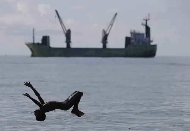 A boy does a flip off a makeshift raft into polluted sea water as he plays in the Philanthrope neighborhood of Les Cayes, Haiti, Monday, October 17, 2016. Many houses in the seaside fishing community lost their roofs and others were completely destroyed. Some of the residents have sought shelter at nearby Philippe Guerrier high school, but they have been told they have to leave so classes can restart. (Photo by Rebecca Blackwell/AP Photo)