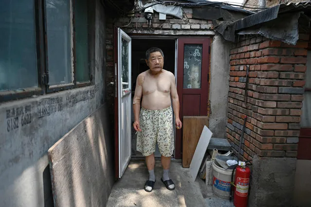 A man cools off in the shade outside his home during a heatwave in Beijing on June 23, 2023. (Photo by Greg Baker/AFP Photo)
