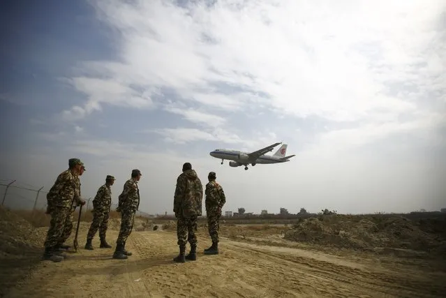 Nepalese army soldiers stand inside the Tribhuvan International Airport as Air China Airbus A319 passenger jet lands near the runway where expansion of Nepal's only international airport is underway, in Kathmandu January 27, 2015. (Photo by Navesh Chitrakar/Reuters)