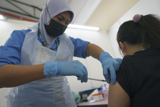 A health worker administers the Pfizer COVID-19 vaccine to a health staff member at a vaccination center in Serdang, outskirt of Kuala Lumpur, Malaysia, Thursday, March 4, 2021. (Photo by Vincent Thian/AP Photo)