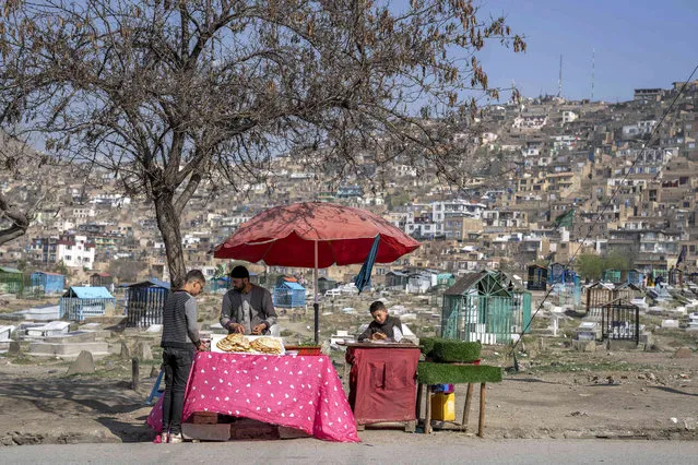 An Afghan man sells bread, during celebration of Nowruz, the Persian New Year, in a cemetery in Kabul, Afghanistan, Tuesday, March 21, 2023. Nowruz is celebrated on the first day of spring in countries including Afghanistan, Tajikistan, and Iran. (Photo by Ebrahim Noroozi/AP Photo)