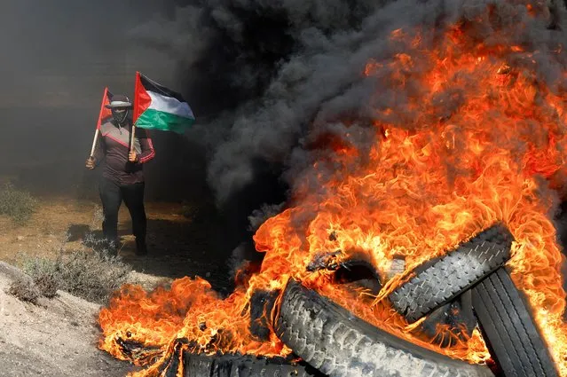 A Palestinian holds flags during a protest against Israeli army raid in Jenin, along Israel-Gaza border fence east of Gaza City on July 3, 2023. (Photo by Mohammed Salem/Reuters)