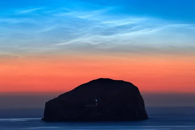 Noctilucent clouds, illuminated from beyond the horizon by the setting sun, over Bass Rock, East Lothian, at 1am, July 12, 2018. (Photo by Tom Duffin/South West News Service)