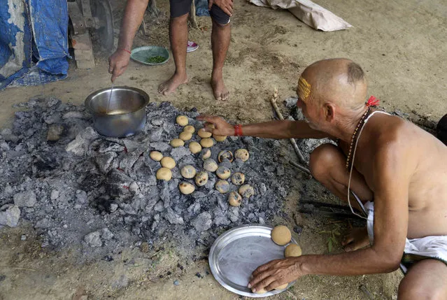 A man prepares litti bati on the outskirts of Prayagraj, in the northern Indian state of Uttar Pradesh, India, Wednesday, July 8, 2023. (Photo by Rajesh Kumar Singh/AP Photo)