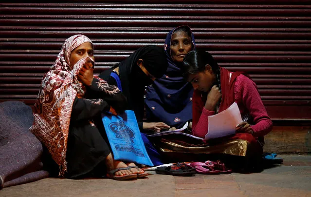 A family checks their documents as they sit outside a bank in the early hours to exchange their old high-denomination banknotes, in the old quarters of Delhi, India, November 16, 2016. (Photo by Adnan Abidi/Reuters)