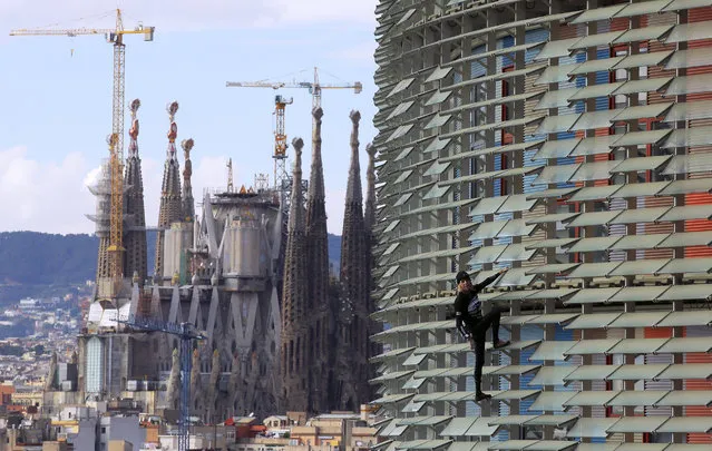 French urban climber, Alain Robert, also known as “French Spiderman”, right, scales the 145 meters (475 ft) of the Agbar tower with the La Sagrada Familia Basilica designed by architect Antoni Gaudi in the background, left, in Barcelona, Spain, Friday, November 25, 2016. (Photo by Manu Fernandez/AP Photo)