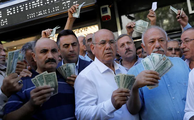 Businessmen holding U.S. dollars stand in front of a currency exchange office in response to the call of Turkish President Tayyip Erdogan on Turks to sell their dollar and euro savings to support the lira, in Ankara, Turkey on August 14, 2018. (Photo by Umit Bektas/Reuters)