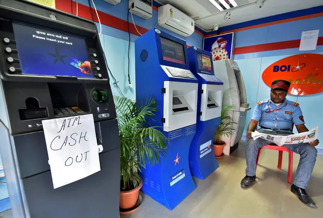A security guard reads a newspaper inside an ATM counter as a notice is displayed on an ATM in Guwahati, India, November 27, 2016. (Photo by Anuwar Hazarika/Reuters)