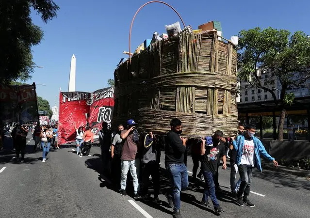 Demonstrators carry a basket with basic products made of cardboard in front of the Buenos Aires' Obelisk as a protest to demand better wages and economic conditions, in Buenos Aires, Argentina on April 13, 2021. (Photo by Agustin Marcarian/Reuters)