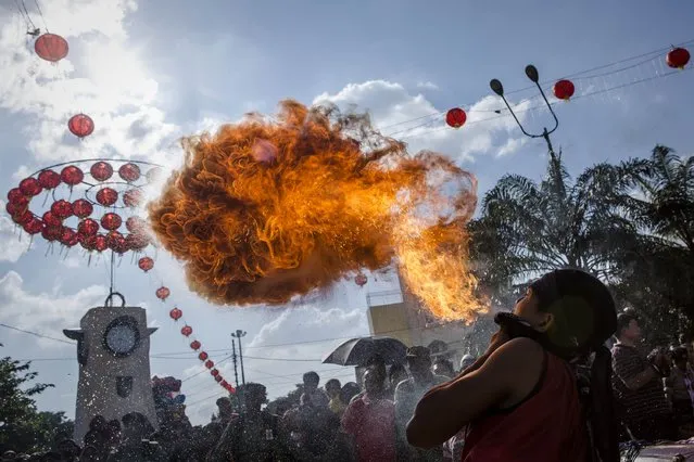 A participant breathes fire during a parade at the Grebeg Sudiro festival on February 15, 2015 in Solo City, Central Java, Indonesia. The Grebeg Sudiro festival represents a harmonious relationship between the Chinese and Javanese communities. People bring offerings known as gunungan, including Chinese sweetcakes piled up into the shape of mountains, which are paraded in the streets followed by Chinese and Javanese performers. (Photo by Ulet Ifansasti/Getty Images)
