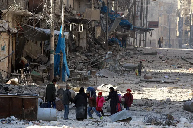 Syrians walk over rubble of damaged buildings, while carrying their belongings, as they flee clashes between government forces and rebels in Tariq al-Bab and al-Sakhour neighborhoods of eastern Aleppo towards other rebel held besieged areas of Aleppo, Syria November 28, 2016. (Photo by Abdalrhman Ismail/Reuters)