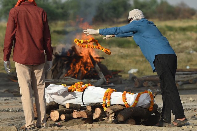 Relatives perform the last rites before the cremation of their loved one who died due to the Covid-19 coronavirus at a cremation ground in Allahabad on May 4, 2021. (Photo by Sanjay Kanojia/AFP Photo)