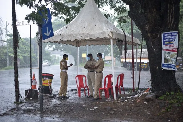 Policemen enforcing a lockdown to curb the spread of coronavirus stand beneath a rain shelter in Kochi, Kerala state, India, Sunday, May 16, 2021. A severe cyclone is roaring in the Arabian Sea off southwestern India with winds of up to 140 kilometers per hour (87 miles per hour), already causing heavy rains and flooding that have killed at least four people, officials said Sunday. (Photo by R.S. Iyer/AP Photo)