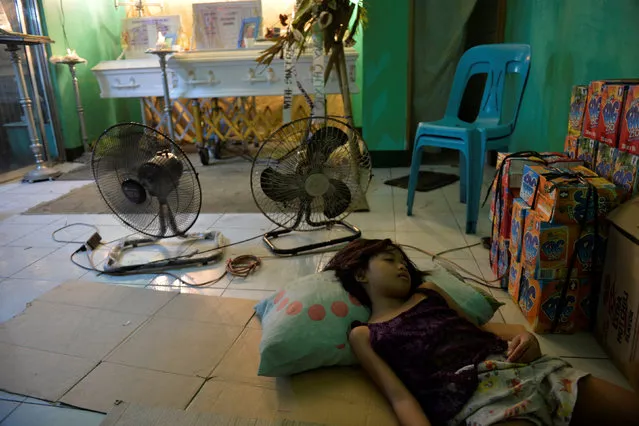 A girl sleeps on the floor near coffins containing the bodies of Domingo Manosca, who according to relatives was a drug user, and his 5-year-old son Francisco Manosca, during their wake inside a village community centre in Pasay city, Metro Manila, Philippines, December 20, 2016. According to relatives and neighbors, unidentified gunmen opened fire in their home, killing both the father and child. (Photo by Ezra Acayan/Reuters)