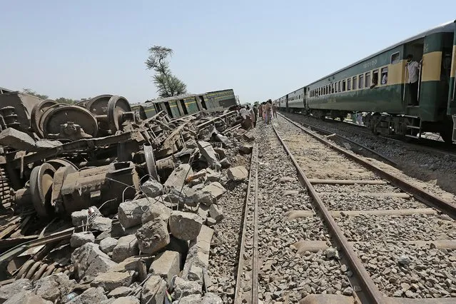 Passengers (R) look out from a window of a train as they travel next to the wreckage of a train after a restoration of the rail track in Daharki on June 8, 2021, a day after a packed inter-city train ploughed into another express that had derailed, killing at least 63 people. (Photo by Shahid Saeed Mirza/AFP Photo)