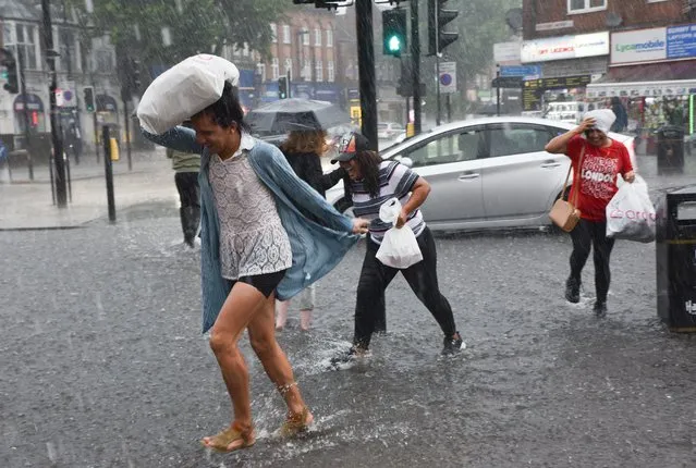 People dash for shelter in Turnpike Lane North London, United Kingdom on July 12, 2021. (Photo by Matthew Chattle/Rex Features/Shutterstock)