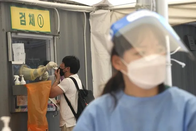 A medical worker in a booth takes a nasal sample from a man during coronavirus testing at a makeshift testing site in Seoul, South Korea, Thursday, July 22, 2021. South Korea is reporting 1,842 newly confirmed coronavirus cases for the previous 24 hours – setting a new pandemic single-day record for the second straight day. (Photo by Ahn Young-joon/AP Photo)