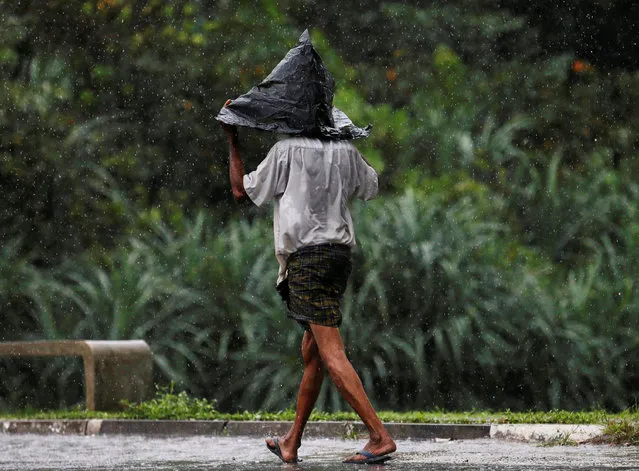 A man covers his head with a plastic bag as he walks along a road in the rain in Colombo, Sri Lanka November 4, 2016. (Photo by Dinuka Liyanawatte/Reuters)