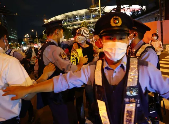 Demonstrators clash with police officers outside the National Stadium during the opening ceremony of the Tokyo 2020 Olympic Games in Tokyo, Japan, on Friday, July 23, 2021. For the first time in history, events at Tokyo 2020 will be held without spectators and winners will place their own medals around their necks. (Photo by Issei Kato/Reuters)