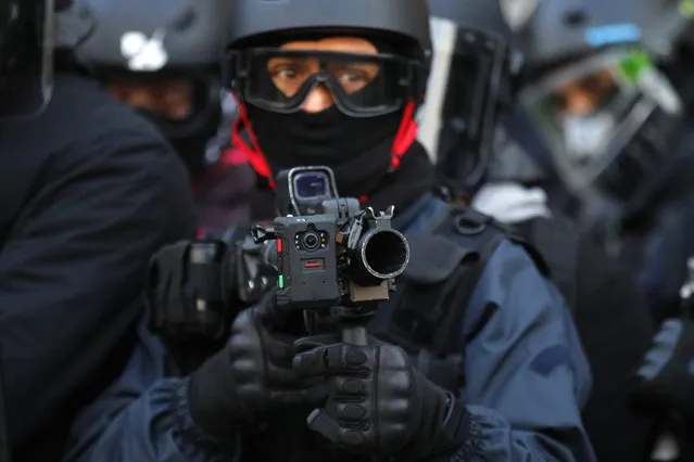 A police officer holds a high-velocity rubber bullets for crowd control equipped with a camera during a yellow vest protest Saturday, February 2, 2019 in Paris. France's yellow vest protesters are taking to the streets to keep pressure on French President Emmanuel Macron's government, for the 12th straight weekend of demonstrations. This week, demonstrators in the French capital are planning to pay tribute to the yellow vests injured during clashes with police. (Photo by Francois Mori/AP Photo)