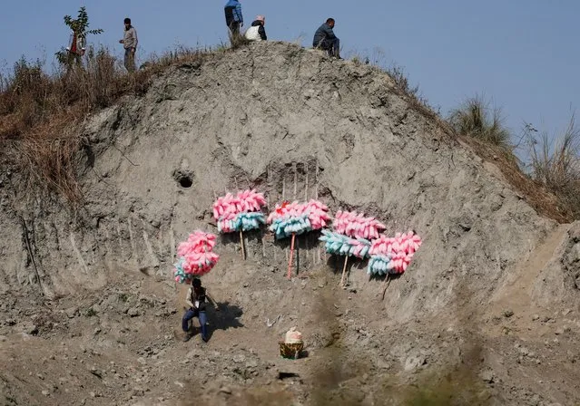 A vendor carrying cotton candies heads toward the Tamu Lhosar celebration parade, a New Year festival of the Gurung community in Kathmandu, Nepal on December 31, 2023. (Photo by Navesh Chitrakar/Reuters)