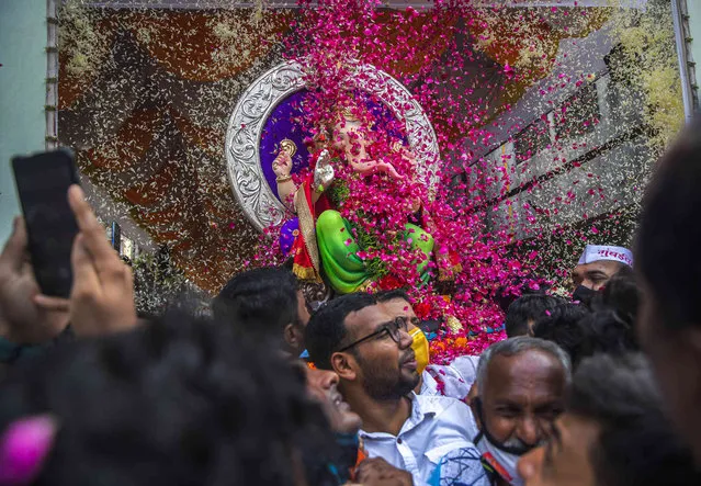Devotees throw flower petals on an idol of elephant-headed Hindu god Ganesha that is taken for immersion on the final day of the ten-day long Ganesh Chaturthi festival in Mumbai, India, Sunday, September 19, 2021. The festival is a celebration of the birth of Ganesha, the Hindu god of wisdom, prosperity and good fortune. (Photo by Rafiq Maqbool/AP Photo)