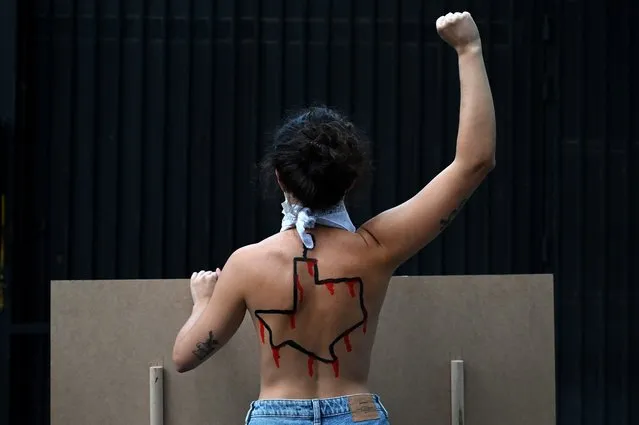 A Femen activist with the US state of Texas drawn on her back protests against the new abortion law in Texas in front of the US consulate in Madrid on September 28, 2021. Texas Governor Greg Abbott lauded another new abortion law that tightens limits on abortion-inducing medications, creating an additional layer of restrictions after a near-total ban on abortion. The new restrictions, which take effect in December 2021, shrinks the window when doctors and clinics in Texas can give abortion-inducing medication from 10 weeks to seven weeks and prohibits the pills from being delivered by mail. (Photo by Gabriel Bouys/AFP Photo)