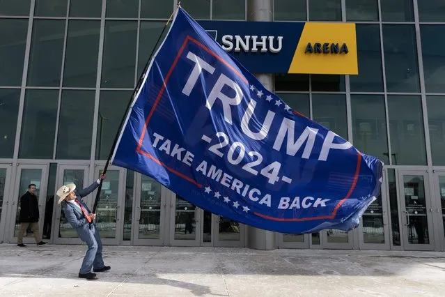 A supporter of former US President Donald J. Trump holds a large flag while waiting in frigid temperatures with other Trump supporters outside SNHU Arena before a Trump campaign rally in Manchester, New Hampshire, USA, 20 January 2024. The New Hampshire primary is held 23 January 2024 and is the second contest in the nominating process of the Republican presidential nomination. (Photo by Michael Reynolds/EPA)