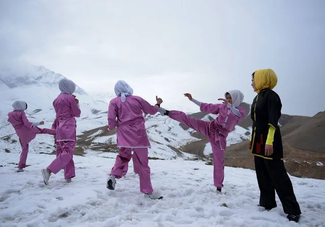 In this photograph taken on January 29, 2017, Afghan members of a Wushu martial arts group display their skills as they pose for a photograph at the Shahrak Haji Nabi hilltop overlooking Kabul. Afghanistan's first female Wushu trainer, Sima Azimi, 20, is training 20 Afghan girls aged between 14-20 at a Wushu club in Kabul, after learning the sport while living as a refugee in Iran. (Photo by Wakil Kohsar/AFP Photo)